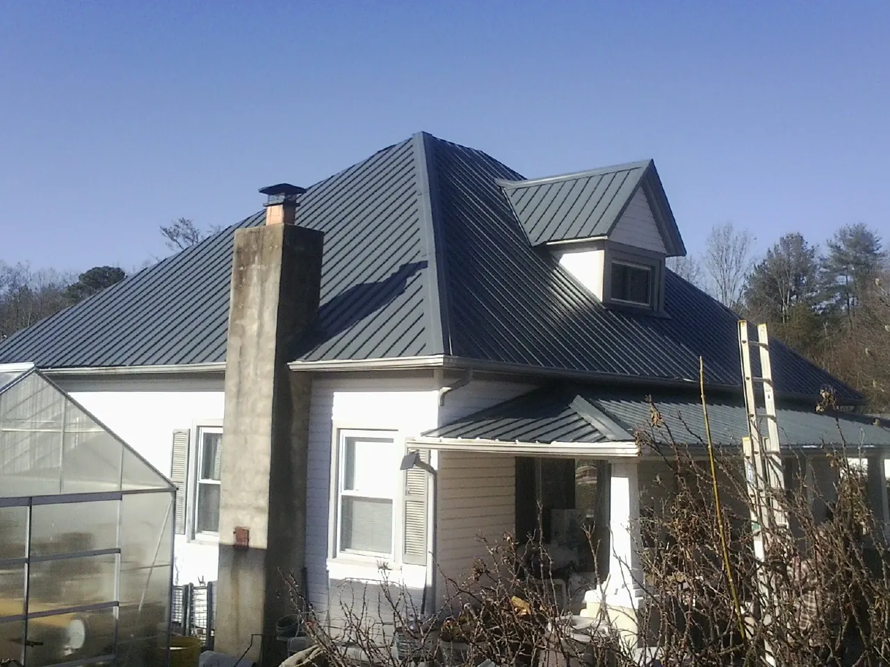 Dark blue standing seam metal roof on a white farmhouse with dormer — Slate & Tile Roof Repair by Roofing Brothers in Bridgewater