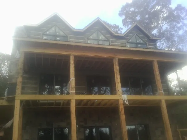 Dormers and porch framing on a large log home under construction — Roof Coating work by our crew in Bridgewater